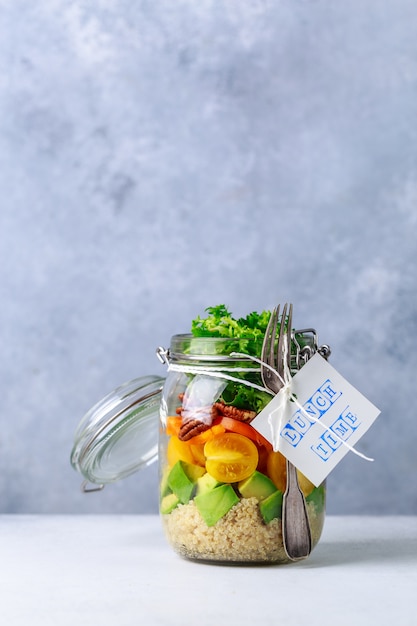 Salada caseira em frasco de vidro com quinoa e legumes com etiqueta hora do almoço sem plástico e tirar o conceito