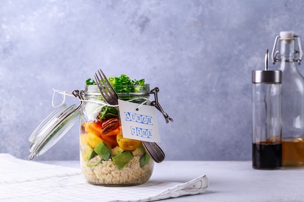 Salada caseira em frasco de vidro com quinoa e legumes com etiqueta hora do almoço sem plástico e tirar o conceito