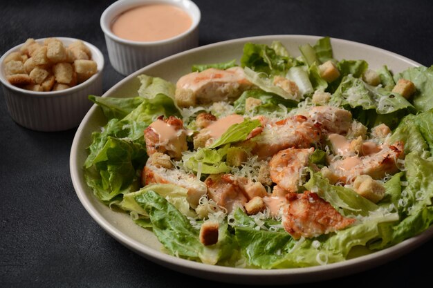 Salada César com Frango Grelhado, Queijo e Croutons com Alface, no Prato. Peitos de frango grelhados e legumes frescos no prato.