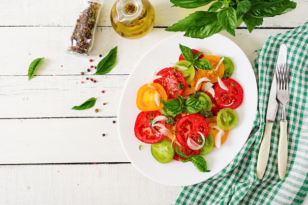 Salada colorida do tomate com cebola e pesto da manjericão. comida vegana.