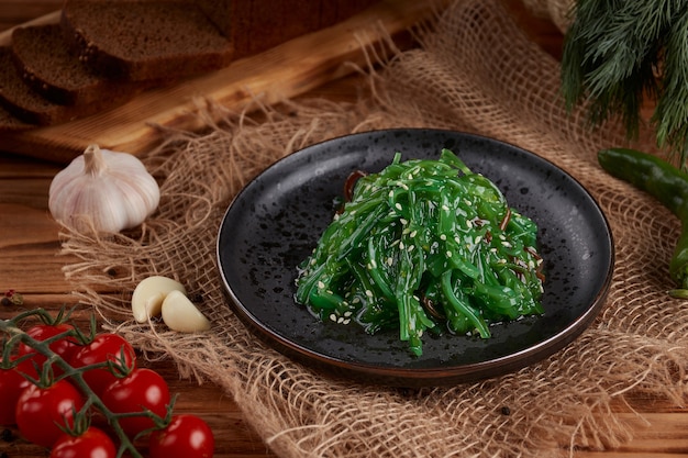 Salada com algas e gergelim no prato de madeira