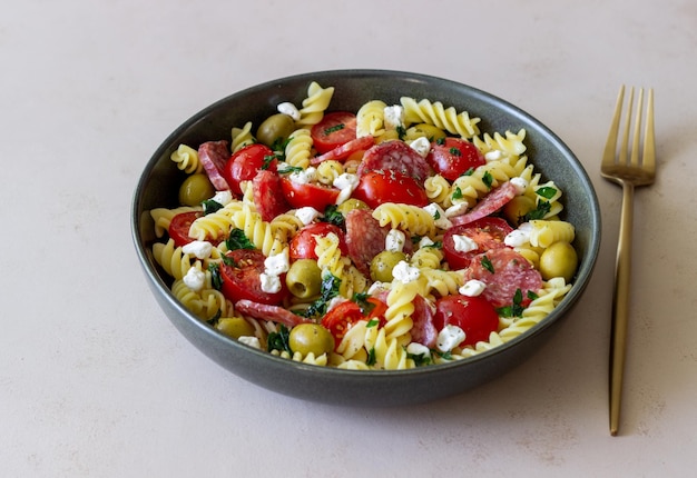 Salada com azeitonas de salsicha de massa fusilli e requeijão comida italiana