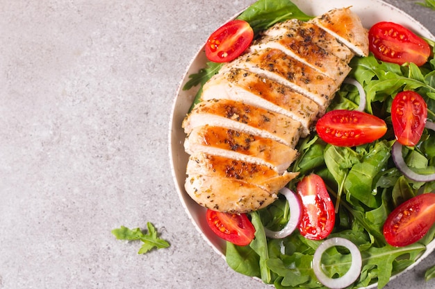 Salada com carne de filé de frango grelhado, legumes frescos, espinafre, rúcula, cebola roxa e tomate.