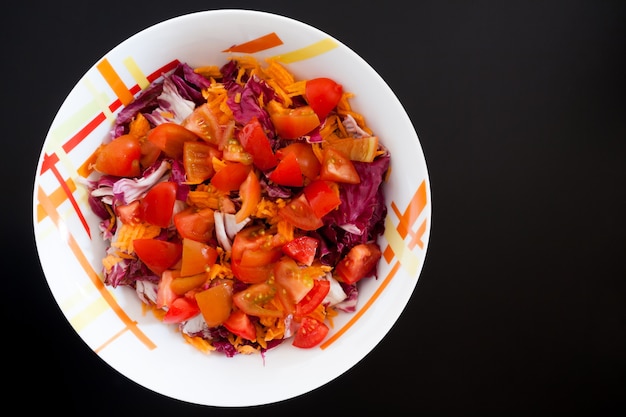 Salada com cenoura e tomate na mesa preta, vista superior. Fundo alimentar