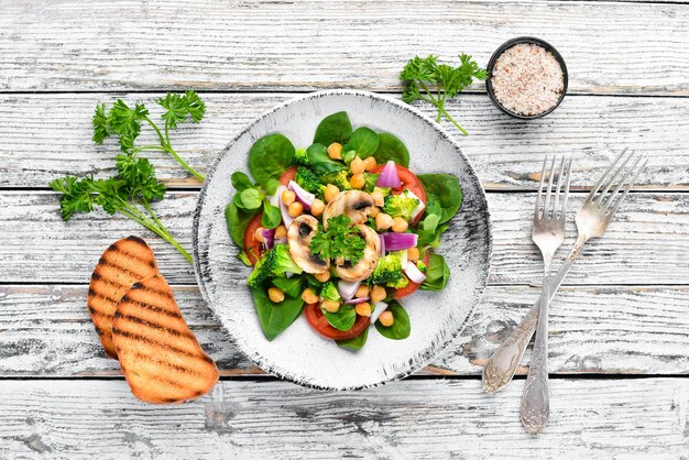 Salada com cogumelos espinafre Ervilhas turcas e cebola em um prato sobre um fundo de madeira Vista superior Espaço livre para o seu texto Postura plana