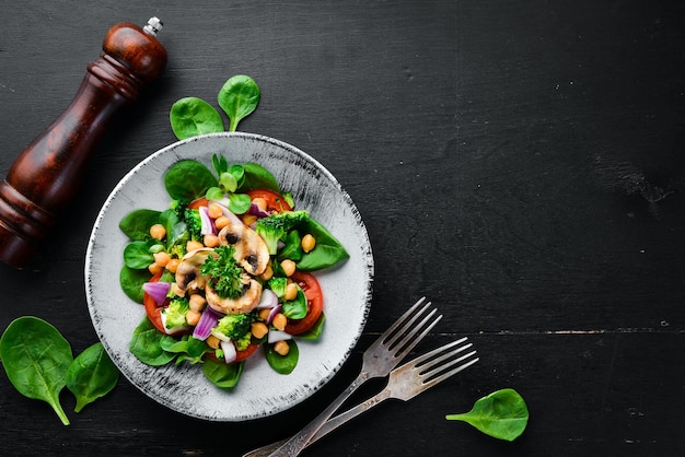 Salada com cogumelos espinafre Ervilhas turcas e cebola em um prato sobre um fundo de madeira Vista superior Espaço livre para o seu texto Postura plana