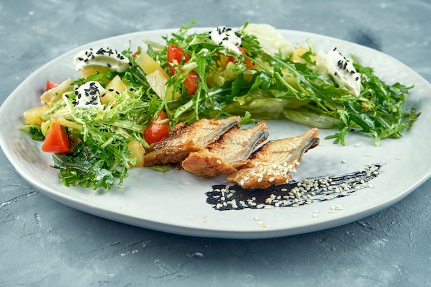 Salada com enguia, rúcula, folhas e cream cheese em prato branco. Salada de frutos do mar