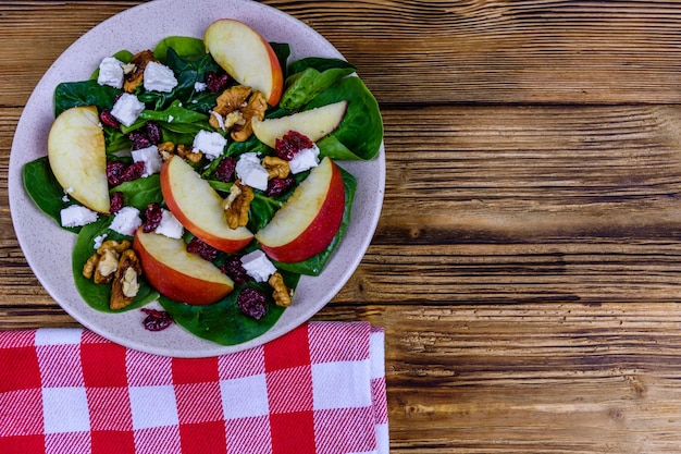 Salada com folhas de espinafre queijo feta cranberries nozes e maçã em um prato de cerâmica Vista superior