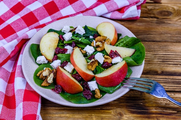 Salada com folhas de espinafre queijo feta cranberries nozes e maçã em um prato de cerâmica