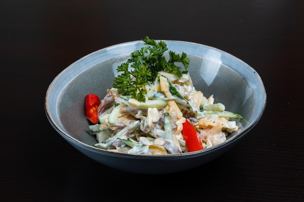 Salada com legumes de carne e maionese em um fundo preto