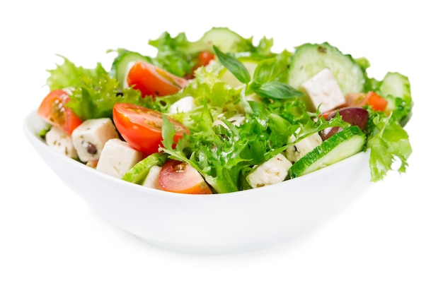 Salada com legumes frescos em uma tigela de cerâmica isolada no fundo branco