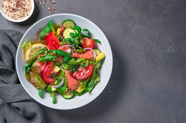 Salada com legumes salmão e ervas frescas em um fundo escuro