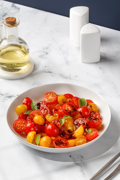 Salada com metades de tomate cereja vermelho e amarelo com molho balsâmico de cobertura de manjericão