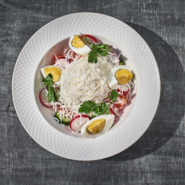 Salada com ovos, queijo e legumes da primavera, rabanetes com tomate. closeup em cima da mesa.