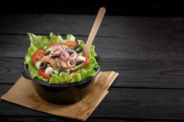 Salada com peixe vermelho ou atum e lettucce em uma tigela de plástico. Fast-food saudável.