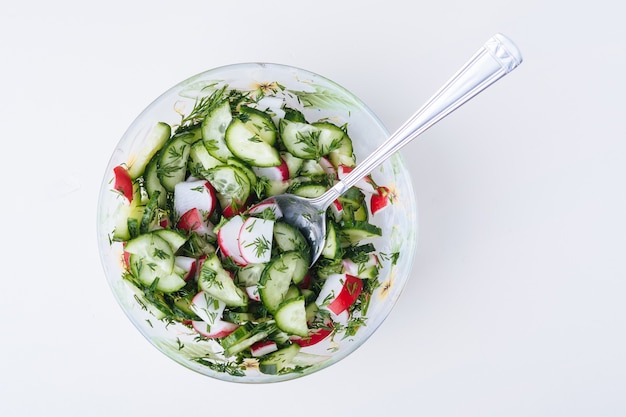 Salada com pepino, rabanete e endro no prato com colher