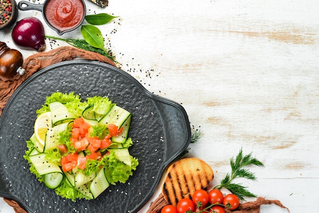 Salada com pepino, salmão e alface Comida saudável em uma placa de pedra preta Vista superior