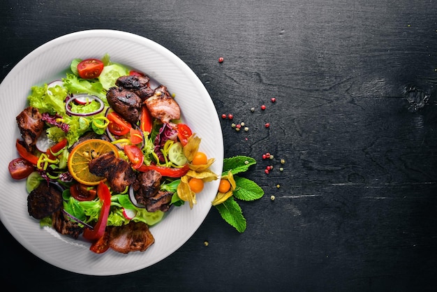 Salada com pepinos frescos, tomates e verduras com carne grelhada em um prato Placa de madeira Vista superior Espaço livre