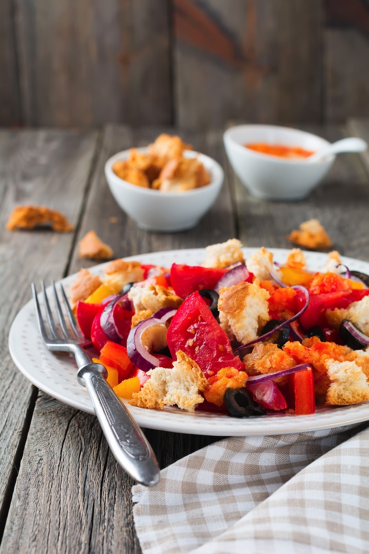 Foto salada com pimentos, tomates, cebolas, azeitonas e croutons com sousomna velha superfície de madeira