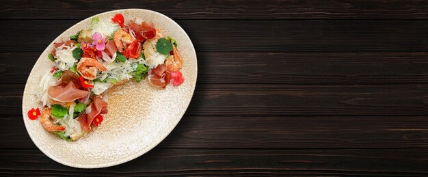 Salada com presunto de camarão e queijo em um prato fundo de madeira