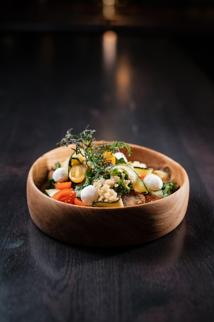 Salada com queijo de legumes e ervas em uma placa de madeira profunda Conceito de pratos estéticos servindo