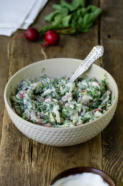 Salada com rabanete, endro e creme de leite sobre um fundo rústico