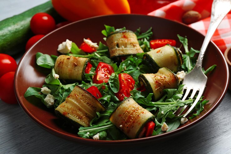 Foto salada com rolos de rúcula e abobrinha no prato no fundo da mesa