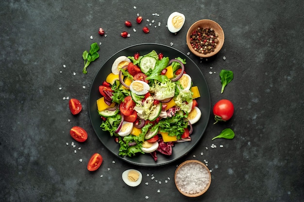 Salada com romã, tomate, pepino fresco, cebola, sementes de gergelim e castanha de caju, especiarias sobre um fundo de pedra. Comida vegetariana saudável.