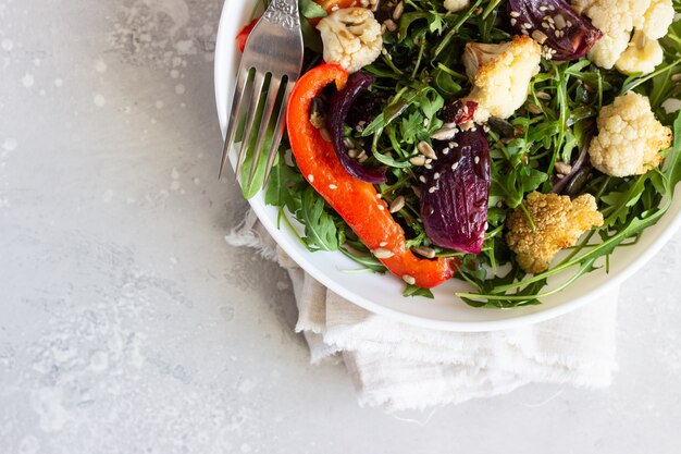 Foto salada com rúcula, legumes assados e sementes