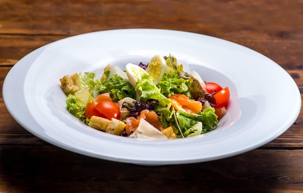 Salada com salmão e legumes em um prato branco