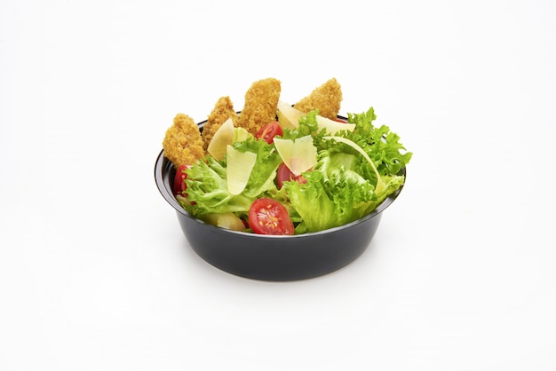 Salada com tiras de frango frito e queijo parmesão fatiado em uma tigela de plástico para levar
