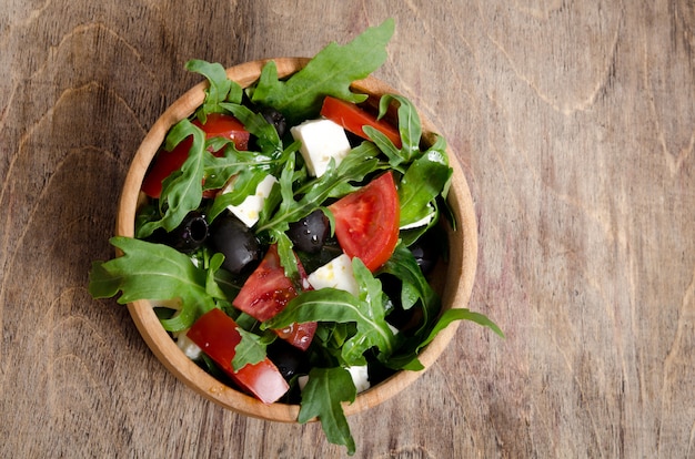 Salada com tomate e azeitonas em fundo de madeira