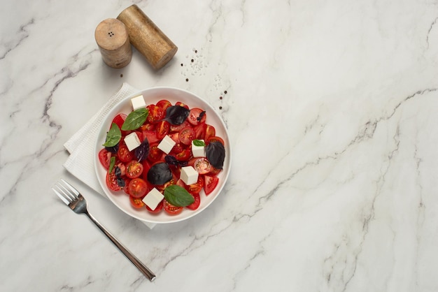 Salada com tomate feta e manjericão em fundo cinzento