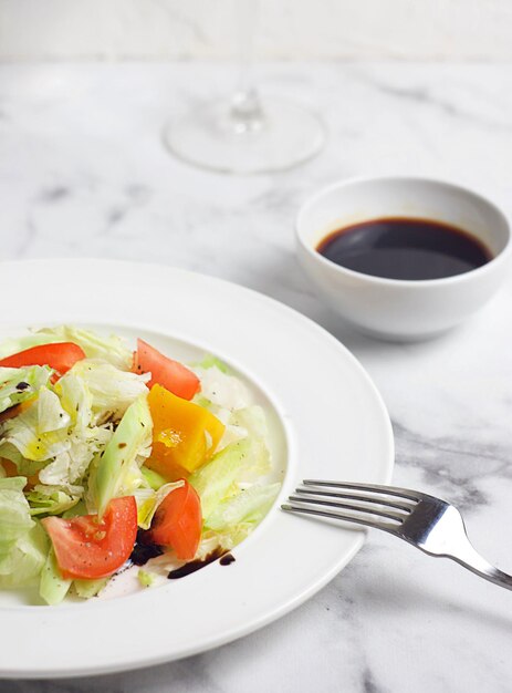 Salada com tomate pepino abóbora repolho em um prato sobre uma mesa de mármore