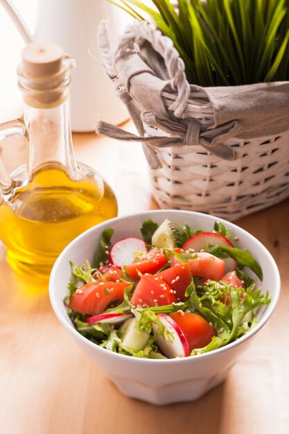 Foto salada com tomate, pepino, rabanete, rúcula e sementes de gergelim com azeite de oliva