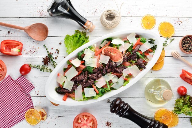 Salada com tomates de espinafre de vitela e queijo parmesão Em um fundo de madeira Vista superior Espaço para cópia grátis