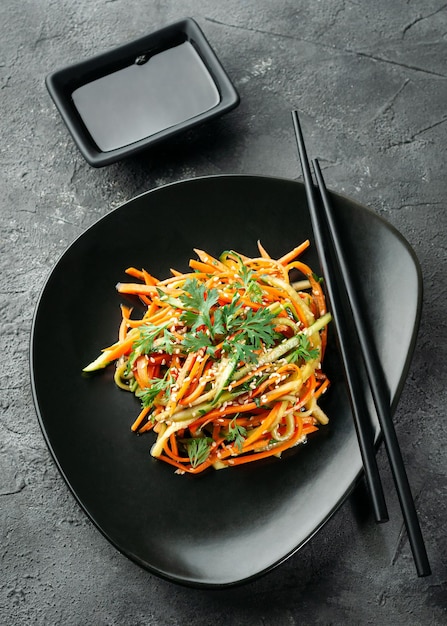 Salada coreana com batatas cruas e legumes Em uma tigela preta Fundo escuro Vista de cima