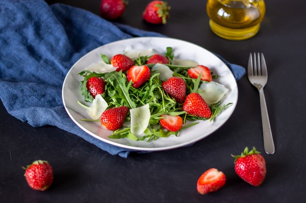 Salada das morangos, da rúcula e do queijo em um fundo escuro. Alimentos dietéticos.