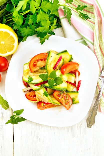 Salada de abobrinha jovem tomate rabanete e hortelã aromatizada com suco de limão e molho de soja em um guardanapo sobre uma placa de madeira clara em cima