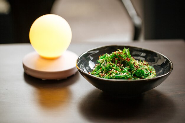 Salada de algas verdes chuka na mesa com um abajur