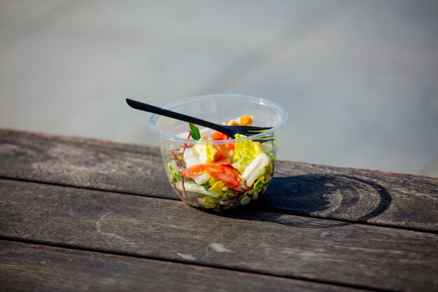 salada de almoço com garfo em caixa de plástico na banch de madeira