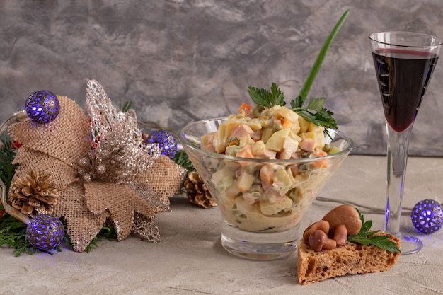 Salada de ano novo russo tradicional Olivier e uma taça de vinho servindo salada de ano novo ou natal