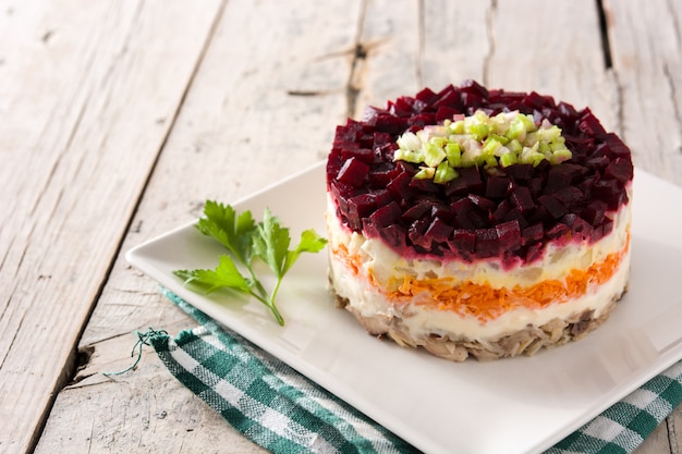 Salada de arenque russa tradicional na mesa de madeira