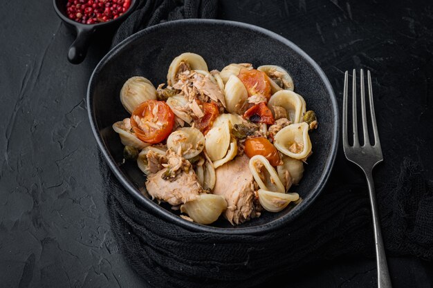 Salada de atum com macarrão e legumes na tigela, mesa preta