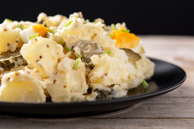 Salada de batata com pepinos, ovo e mostarda na mesa de madeira