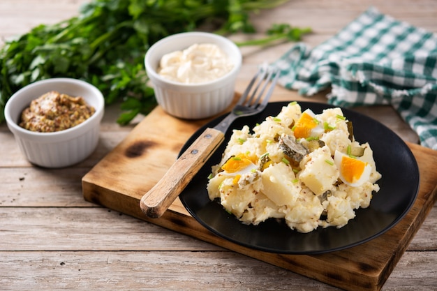 Salada de batata com pepinos, ovo e mostarda na mesa de madeira