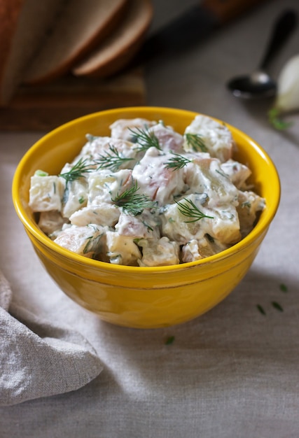 Salada de batata fria tradicional com cebolas e ervas em um fundo de toalha de mesa de linho. estilo rústico.