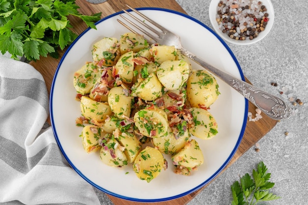 Foto salada de batata quente com bacon, cebola, ervas frescas e molho de vinagre em uma tigela salada de batata alemã