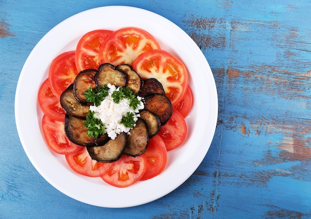 Salada de berinjela com tomates e queijo feta em fundo de madeira