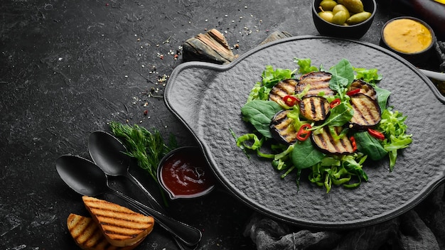 Salada de berinjela, espinafre e repolho em um prato preto Comida vegana Vista superior Estilo rústico